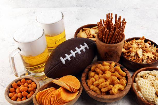 istock Chips, salty snacks, football and Beer on a table. Great for Bowl Game snack projects. 1202043911
