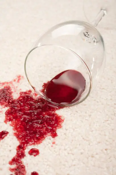 A spilled glass of red wine on a cream coloured carpet