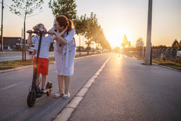 istock Little boy riding a electic push scooter with his mom 1202045981