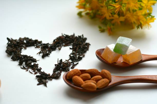 Nuts in the wooden spoons and tea heart  white background