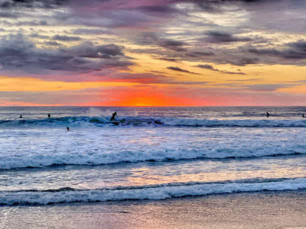 surfers walking on the beach in lahinch county clare ireland as the sun goes down