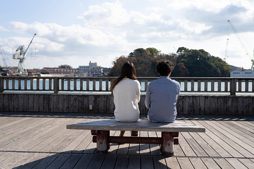 A young couple sitting on a bench and having a fun conversation