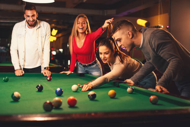 Group of friends play billiards at night out stock photo