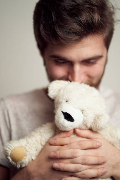 Portrait of a happy young handsome man hugging a plush teddy bear. stock photo