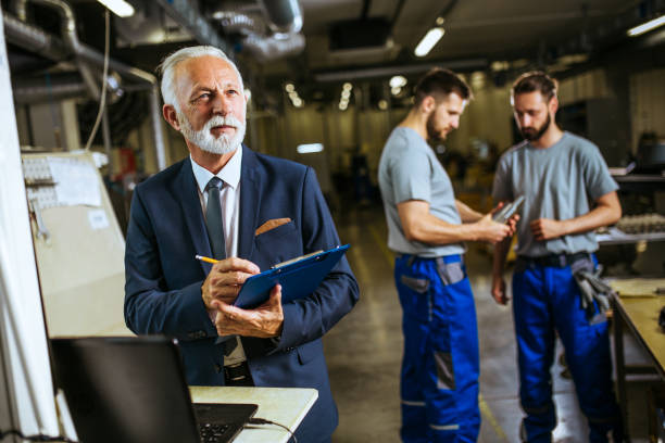 istock Male foreman evaluate work in factory and writing at notepad 1202061491