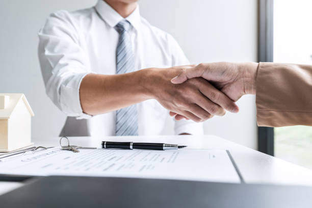 istock Real estate agent and customers shaking hands together celebrating finished contract after signing about home insurance and investment loan, handshake and successful deal 1202062932