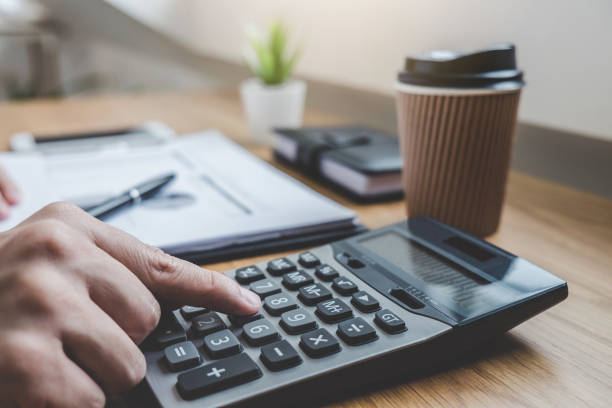 istock Businessman working on a graph document financial report and analysis calculation investment cost with calculator at office desk and other objects around 1202063001