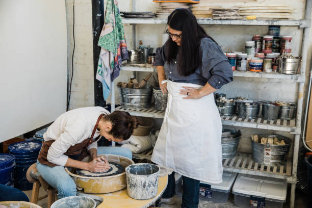 istock An art teacher giving instruction because to a student on a pottery wheel 1202066295