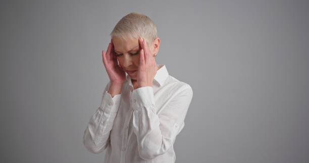 istock Tired elderly woman holding her head on hands feel headache 1202069640