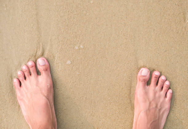 istock Feet of man standing on the beach 1202071768