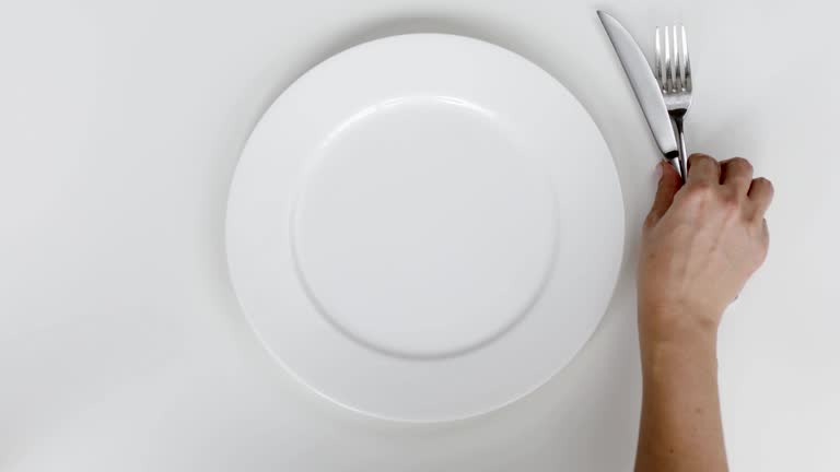 Woman setting up table, a plate and cutlery for meal