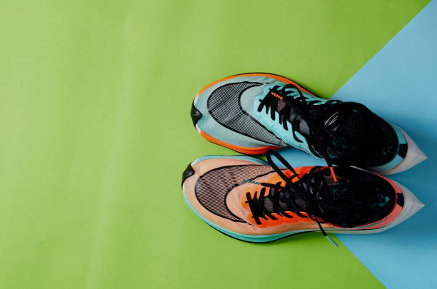 istock Blue and orange running shoes on green floor with copy test space 1202074252
