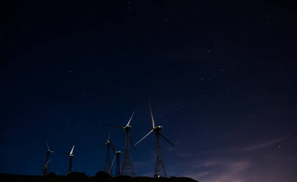 istock A group of white wind generators produces alternative energy by wind is on a black night sky with stars background 1202076502