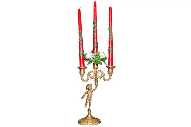 Three-armed candlestick with red candles, held by a figurine, made of brass in old decorative style, isolated on a white background with a clipping path.