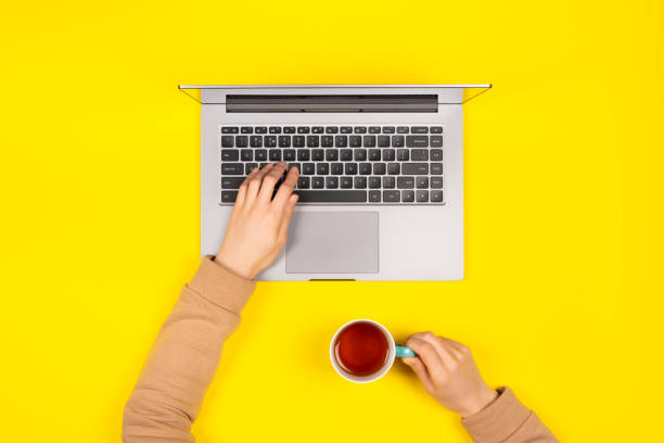 istock Female hands working on new laptop on bright yellow background Top view, flat lay. 1202077478