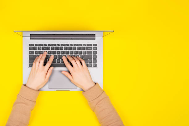 istock Female hands working on new laptop on bright yellow background Top view, flat lay. 1202078314