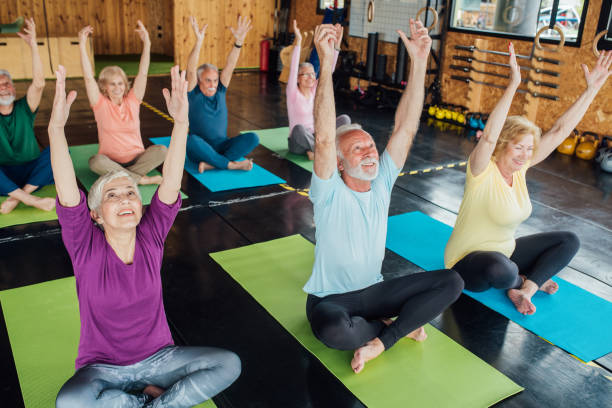 Group of seniors staying active with yoga Group of seniors attending a yoga class. community health center stock pictures, royalty-free photos & images
