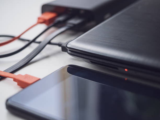 istock Power bank charges your laptop and phone using different cables. Simultaneous charging of different devices. Modern innovative technologies 1202089618