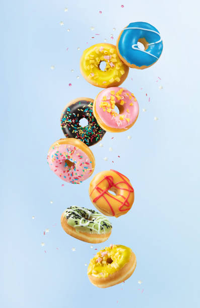 istock Various colorful doughnuts in motion on blue background 1202092043