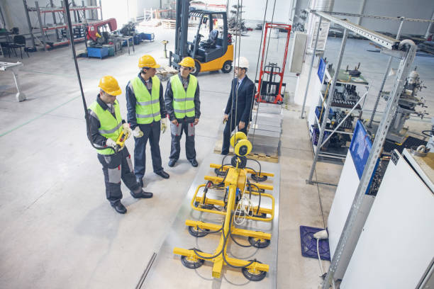 istock Workers and electro magnets lifting steel plate 1202093475