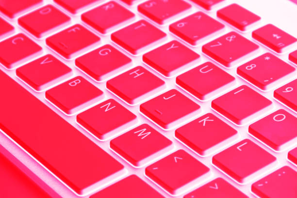 Closeup of a modern computer keyboard keys in red tones. Close up view of a business workplace with wireless computer keyboard. Top view Closeup of a modern computer keyboard keys in red tones. Close up view of a business workplace with wireless computer keyboard. Top view enter key computer keyboard computer key white stock pictures, royalty-free photos & images