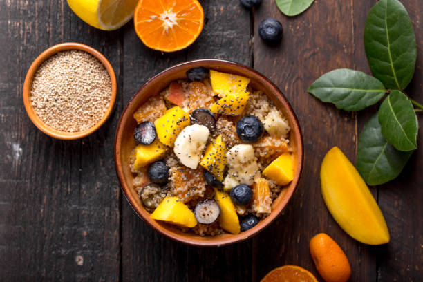 Fresh quinoa organic fruit salad in bowl on wooden  background. Helthy superfood detox concept.  Vegan/vegetarian food. Space for text. Top view stock photo