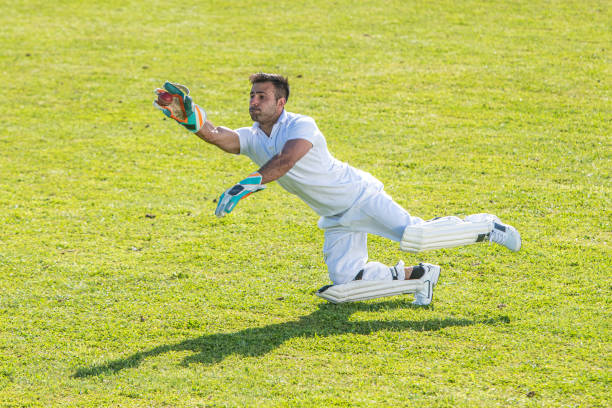 Photo of a middle-eastern cricket player jumping to catch the ball.