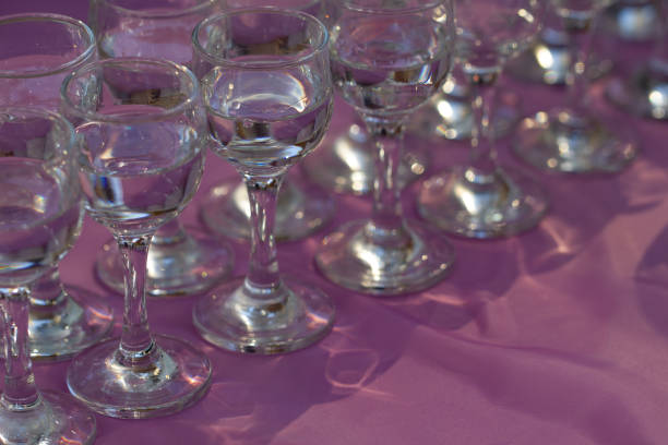istock Glasses with vodka served on lilac table, close up 1202098318