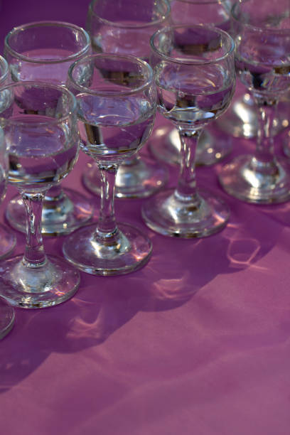 istock Glasses with vodka served on lilac table, close up, vertical orientation 1202098526