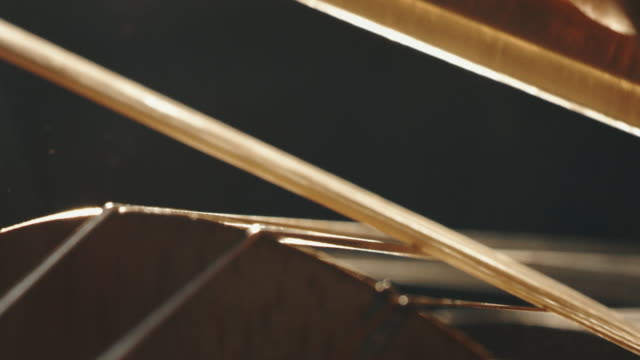 Slow motion artistic macro of master artisan luthier playing with a bow on a handmade violin or cello