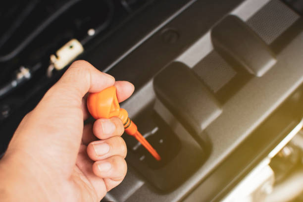 Hand of mechanic has pull yellow dipstick for checking engine oil level.