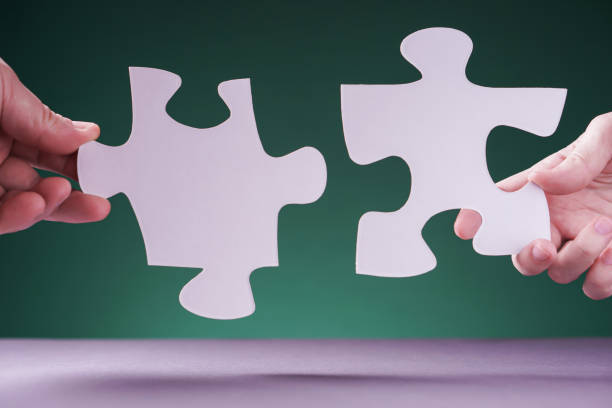 istock Two hands holding puzzle pieces on green background. 1202103723