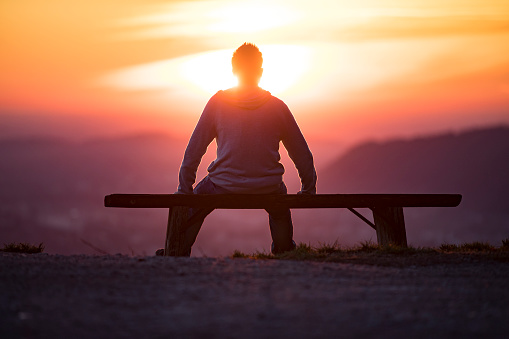 Adult Man Sitting on Bench and Watching Landscape at Sunset.
