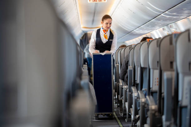 Stewardess from airline Sunexpress, goes with a service wagon through the passenger cabin. Antalya / Turkey - January 24,2020: Stewardess from airline Sunexpress, goes with a service wagon through the passenger cabin. sunexpress stock pictures, royalty-free photos & images