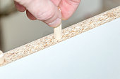 Inserting a wooden dowel into the hole in board chipboard.