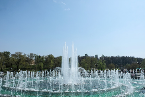a large round shaped fountain works by splashing a large jet of water up/wide horizontal frame