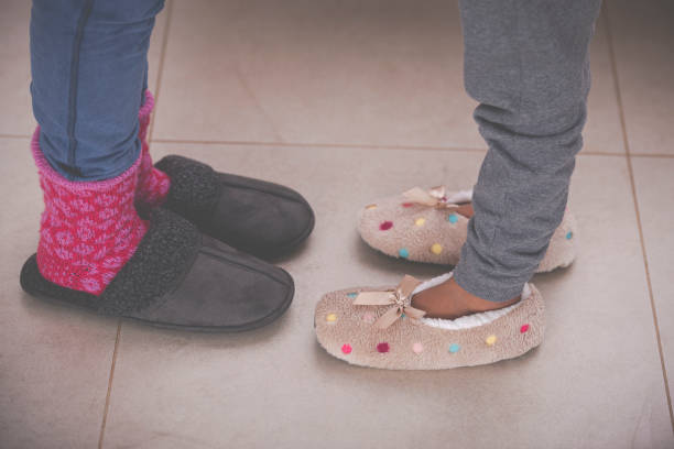 istock Daughter's and mother's feet with warm slippers on a tiled floor. 1202107626
