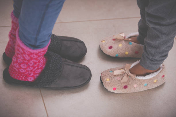 istock Daughter's and mother's feet with warm slippers on a tiled floor. 1202108638