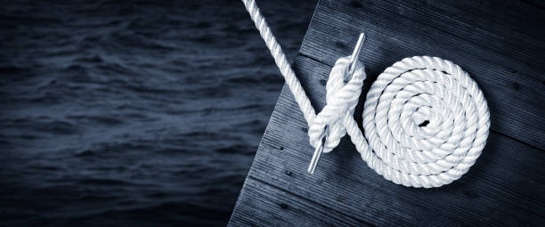 Boat Rope Secured To Cleat On Wooden Dock stock photo