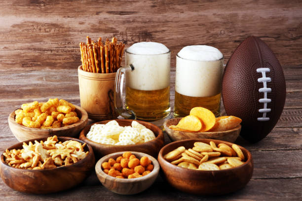 istock Chips, salty snacks, football and Beer on a table. Great for Bowl Game snack projects. 1202111886