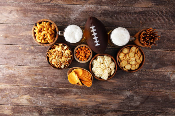 istock Chips, salty snacks, football and Beer on a table. Great for Bowl Game snack projects. 1202111927