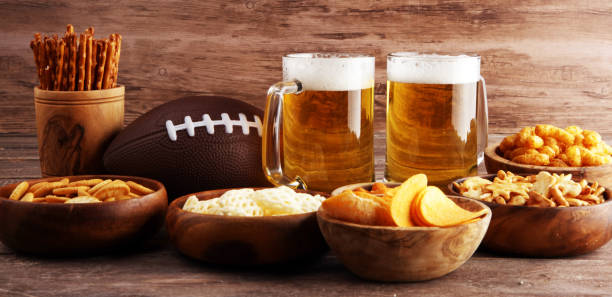 istock Chips, salty snacks, football and Beer on a table. Great for Bowl Game snack projects. 1202111945