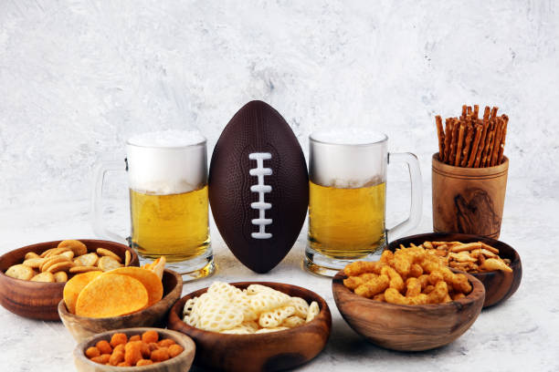 istock Chips, salty snacks, football and Beer on a table. Great for Bowl Game snack projects. 1202113657