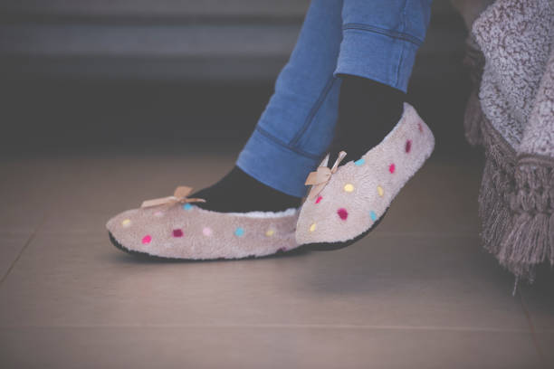 istock Female's feet with slippers sitting on a sofa. 1202114044