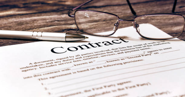 istock Contract sheet with glasses and pen on a wooden background 1202114995