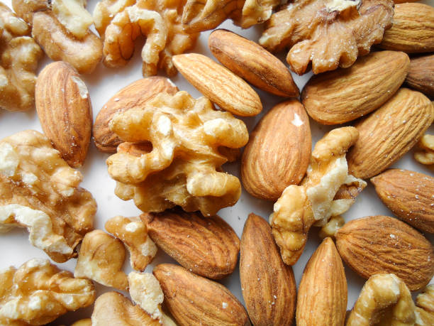 istock fry fruits on white background, almonds and walnuts 1202116752