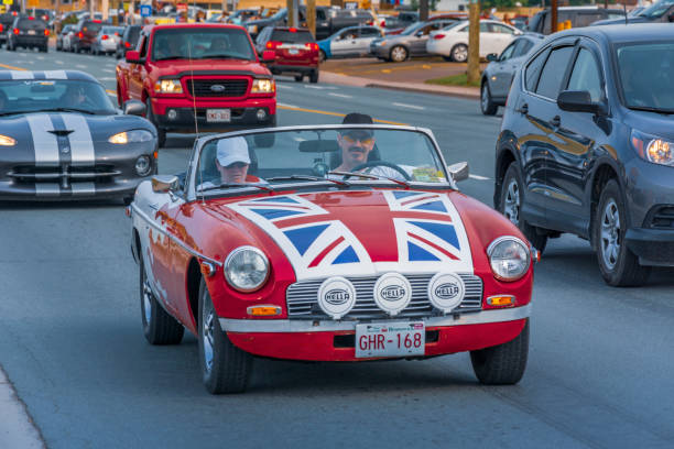 Moncton, New Brunswick, Canada - July 11, 2015 : Male driver and female passenger cruise in a 1976 MGB sports car Saturday evening on Mountain Road during 2015 Atlantic Nationals Automotive Extravaganza.