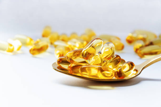 istock Cod liver oil omega 3 gel capsules on a spoon on white background. 1202119190