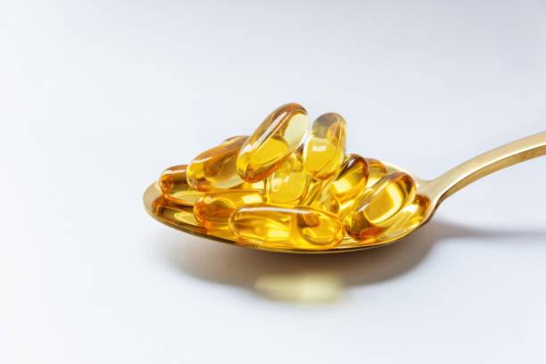 istock Cod liver oil omega 3 gel capsules on a spoon on white background. 1202119210