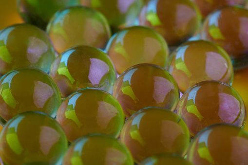 Many yellow glass balls close up view. Abstract transparent sphere
